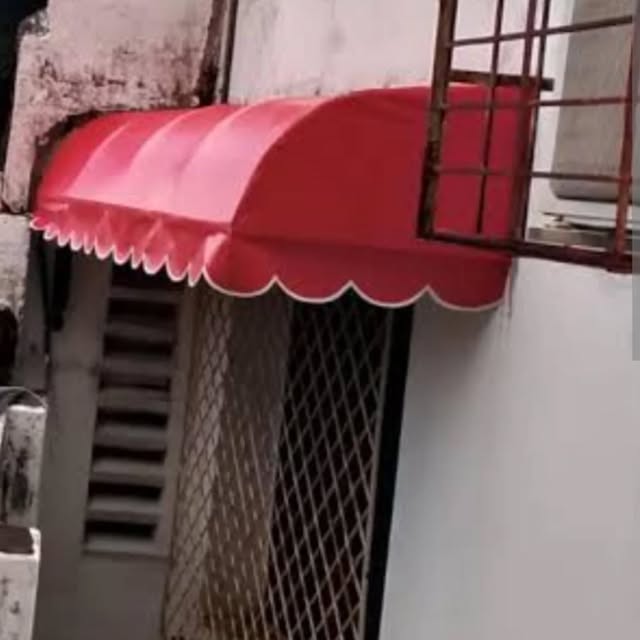 Toldo vermelho curvo sobre porta de entrada