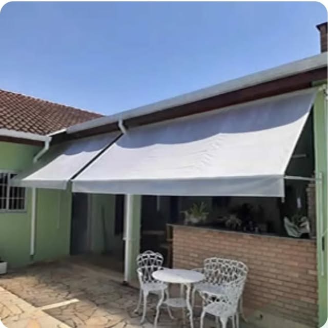 Toldos claros sobre portas de uma área com mesa e cadeiras