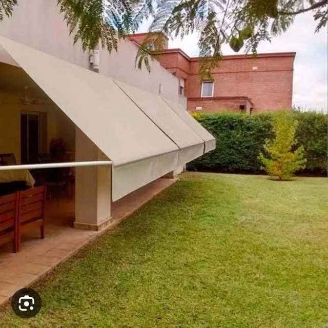 Toldo bege inclinado junto a varanda e gramado